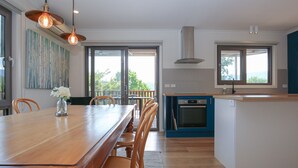 A modern kitchen with a wooden dining table, chairs, and pendant lighting. - BRIGHT VIEWS: Bright (Bright)