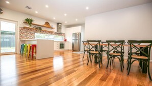 A modern kitchen with wooden flooring, a central island, and a dining area with four chairs. - BRIGHTER STAYS: Bright (Bright)