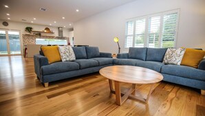 A modern living room with a sectional sofa, a round coffee table, and wooden flooring. - BRIGHTER STAYS: Bright (Bright)