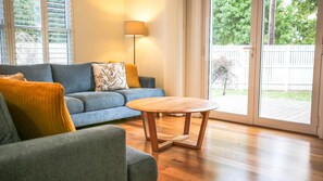 A living room with a blue sofa, a wooden coffee table, and a yellow throw blanket. - BRIGHTER STAYS: Bright (Bright)