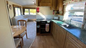 A compact kitchen with wooden cabinets, a stove, and a sink. - Caravan - Sleeps 4 - Pet Friendly - Parking (Newton Stewart)