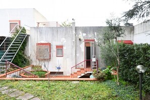 A building with a concrete exterior, a red staircase, and a small garden area. - N232 - Numana, five-room apartment with garden in a residence with swimming pool (Numana)
