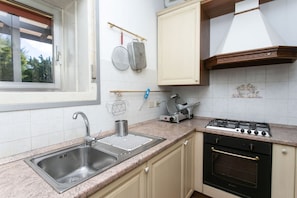 A kitchen with a stainless steel sink, a gas stove, and a window with blinds. - N232 - Numana, five-room apartment with garden in a residence with swimming pool (Numana)