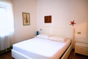A single bed with white bedding, a nightstand with a blue lamp, a small wall decoration, and a star ornament. - N232 - Numana, five-room apartment with garden in a residence with swimming pool (Numana)