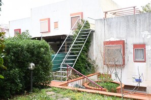 A residential building with a staircase leading to an upper level, surrounded by greenery and a small garden area. - N232 - Numana, five-room apartment with garden in a residence with swimming pool (Numana)