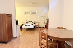 A room with a bed, a dining table, chairs, a wooden cabinet, and two framed pictures on the wall. - N232 - Numana, five-room apartment with garden in a residence with swimming pool (Numana)