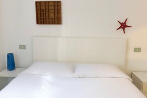 A bed with white bedding, a headboard, a wall-mounted vent, and a red starfish decoration. - N232 - Numana, five-room apartment with garden in a residence with swimming pool (Numana)