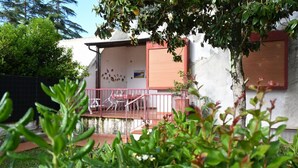 Um edifício residencial com varanda, escadaria e área de jardim.