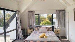 Quarto com cama grande, janela com cortinas, radiador e luminária de teto.