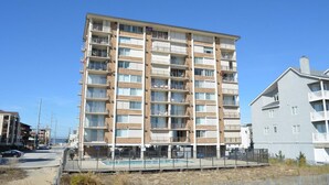 Un edificio residencial de varios pisos con balcones, piscina y zona vallada.