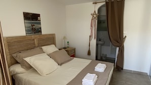 Ein ordentlich bezogenes Bett mit Kopfteil, ein Nachttisch mit Lampe und ein Bild an der Wand.