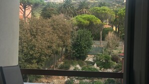 Een balkon met uitzicht op een heuvel, bebouwd met bomen en gebouwen.