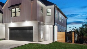 Une maison moderne à deux étages, dotée d’un garage, d’une pelouse bien entretenue et d’une clôture en bois.