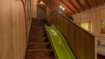 A wooden staircase with a green slide leading to a landing.
