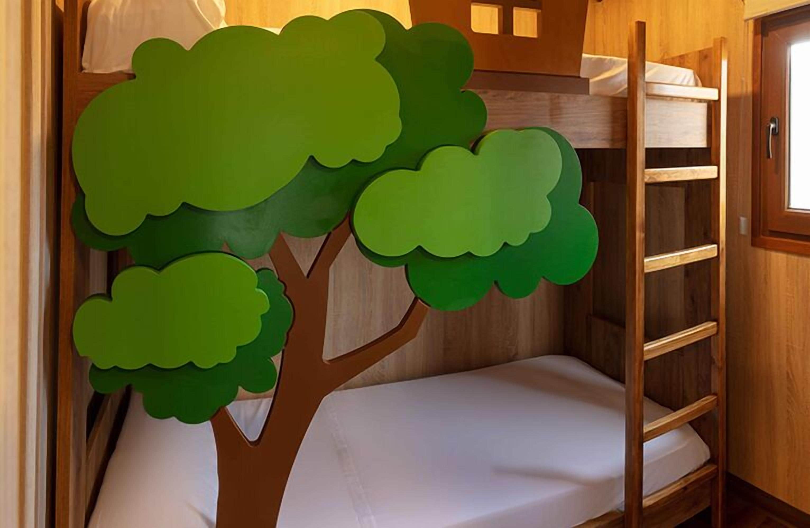 Ein Etagenbett mit einer Holzleiter, einer weißen Matratze und einer baumförmigen Dekoration an der Wand.