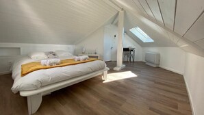 Un dormitorio con cama, tragaluz y suelo de madera.