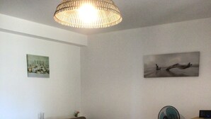Una sala de estar con sofá, mesa, ventilador y lámpara.