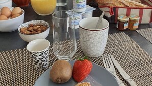 A breakfast table with eggs, bread, fruits, and beverages. - La Villa des Pins 150 m2 at 5 min from the beach with 3 bedrooms and 8 beds (Messanges)