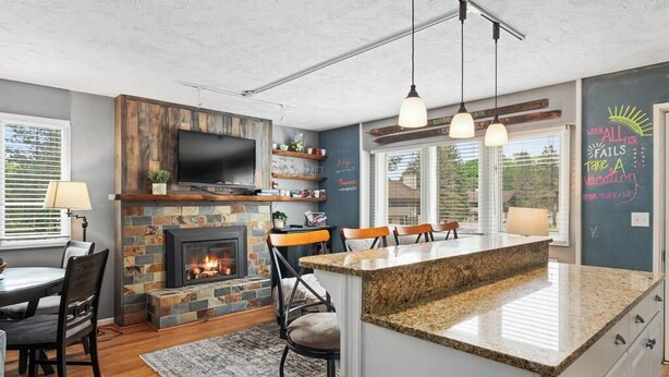 Una cocina moderna con chimenea de piedra, estanterías de madera y una isla grande.