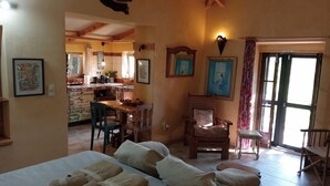 Una habitación acogedora con una cama, una silla, una mesa y una cocina al fondo.