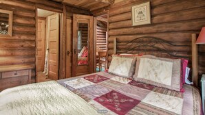 Une chambre dans une cabane en bois, avec un lit, une commode et une chaise.