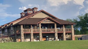 A large, multi-story building with a stone facade, multiple balconies, and a spacious lawn in front.