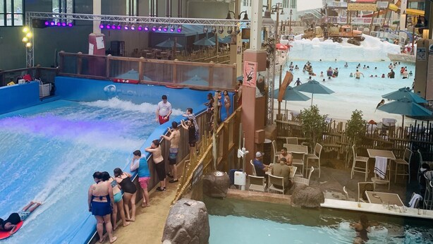 An indoor water park with multiple pools, slides, and a stage area.