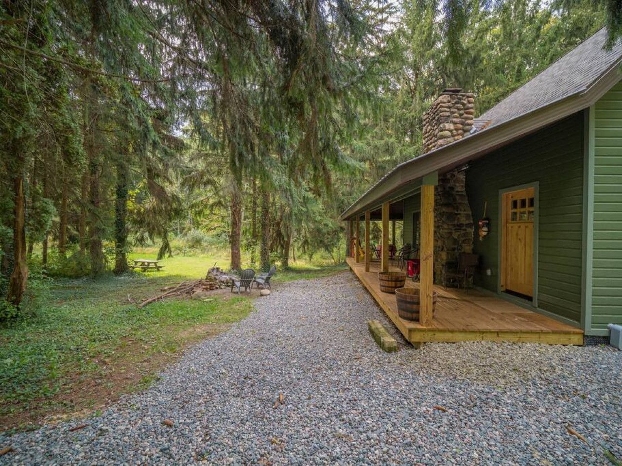 Eine rustikale Holzhütte mit einem Steinkamin, einer Holzterrasse und einem Kiesweg, der davorführt.