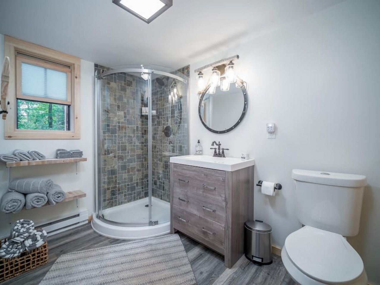 A modern bathroom with a glass-enclosed shower, a wooden vanity, and a toilet.
