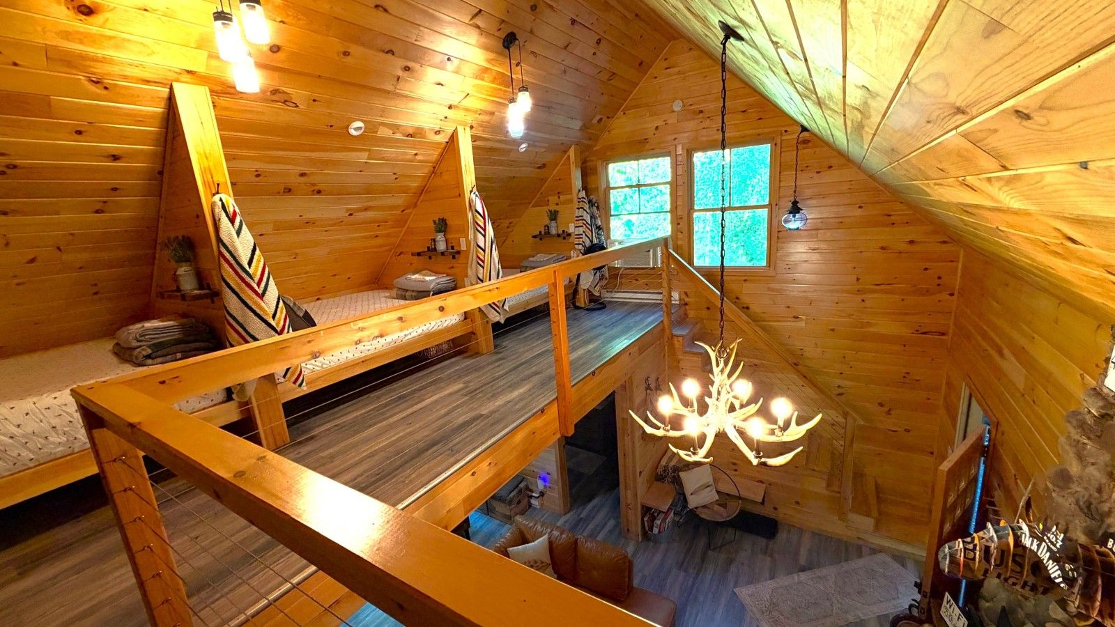 A cabin with a loft bedroom, a staircase, and a chandelier.