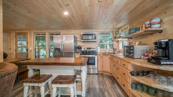 A wooden cabin kitchen with a central island, wooden cabinets, and a built-in microwave.