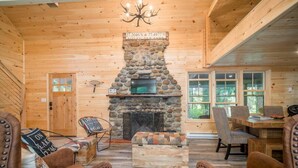 A cozy cabin interior with a stone fireplace, wooden walls, and leather furniture.