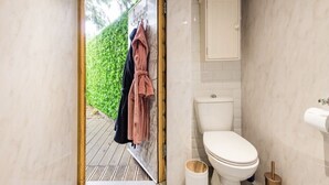 A bathroom with a toilet, a sink, and a towel rack with towels. - The hideaway  (Bristol)