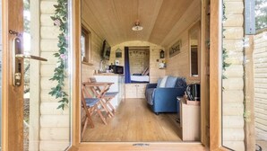 A cozy cabin interior with a wooden floor, a sofa, a dining table with chairs, and a kitchen area. - The hideaway  (Bristol)