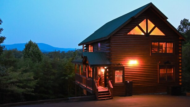 A wooden cabin with a balcony, a staircase leading to the entrance, and a view of the surrounding forest. - MTN views! PoolTable, AirHockey, Foosball, HotTub, FirePit; Perfect for FAMILIES (Sevierville)