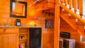 A cozy wooden cabin interior with a kitchen area, a small refrigerator, a coffee maker, a lamp, and a game board. - MTN views! PoolTable, AirHockey, Foosball, HotTub, FirePit; Perfect for FAMILIES (Sevierville)