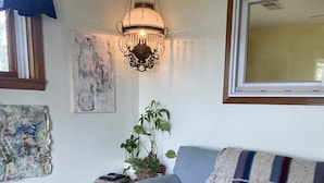 A living room with a blue sofa, a wooden coffee table with a laptop, a green pouf, a plant, and a can of drink. - Bemus Point Lake Front Cottage with Dock (Bemus Point)