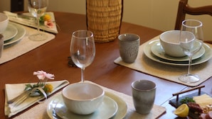 A dining table set with plates, bowls, glasses, and a vase with flowers. - Bemus Point Lake Front Cottage with Dock (Bemus Point)