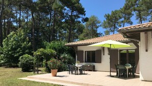 A patio with outdoor seating, a large potted plant, and a pergola with a green umbrella. - Family house with arge garden - peaceful & close to Arcachon Bay - sleeps 6 (Gujan-Mestras)