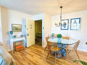 Zona pranzo con tavolo rotondo, sedie, un lampadario e quadri appesi al muro.