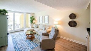 Un salon comprenant un canapé, un fauteuil, une table basse et un tapis à motifs.