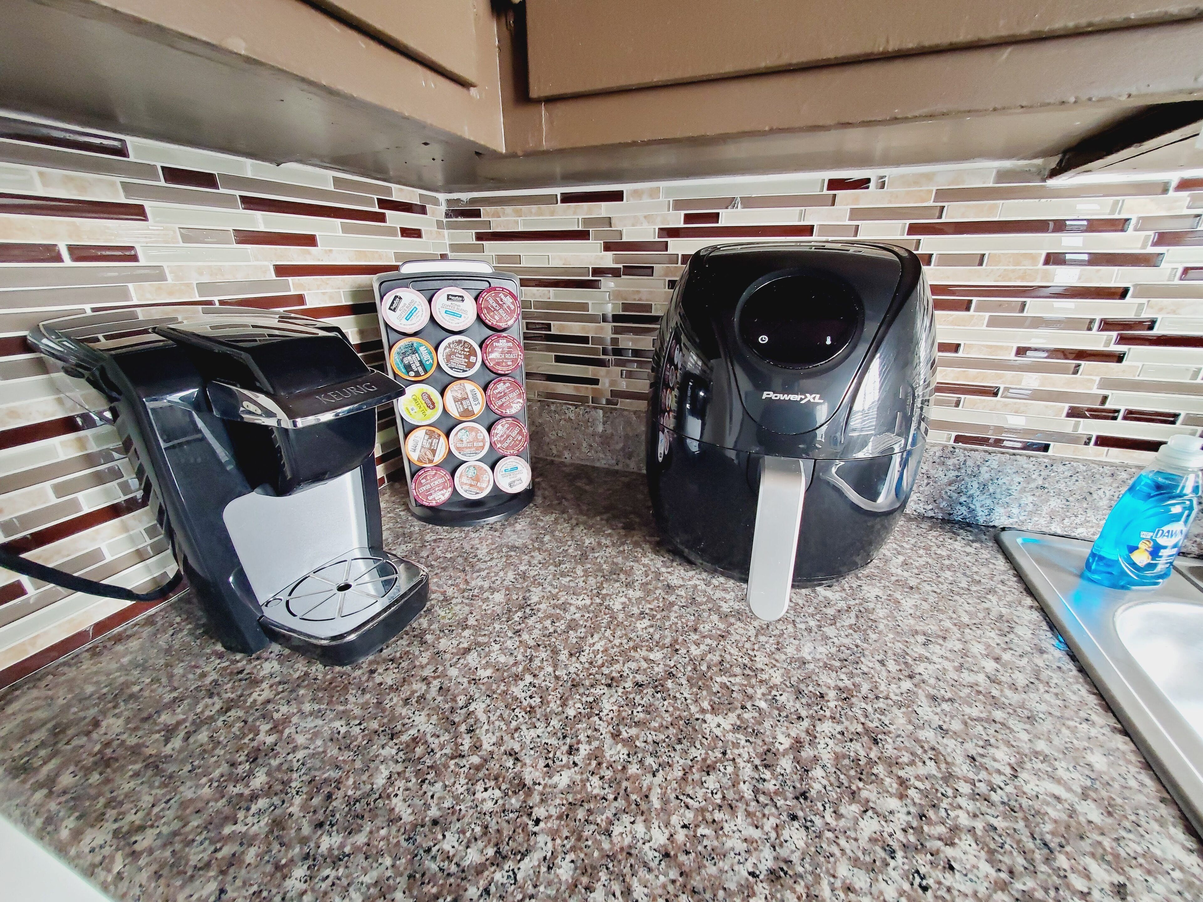 Una cocina con cafetera, máquina Keurig y dispensador de agua sobre una encimera de granito.