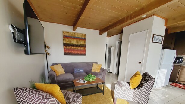 Een woonkamer met een bank, twee fauteuils, een salontafel en een televisie.