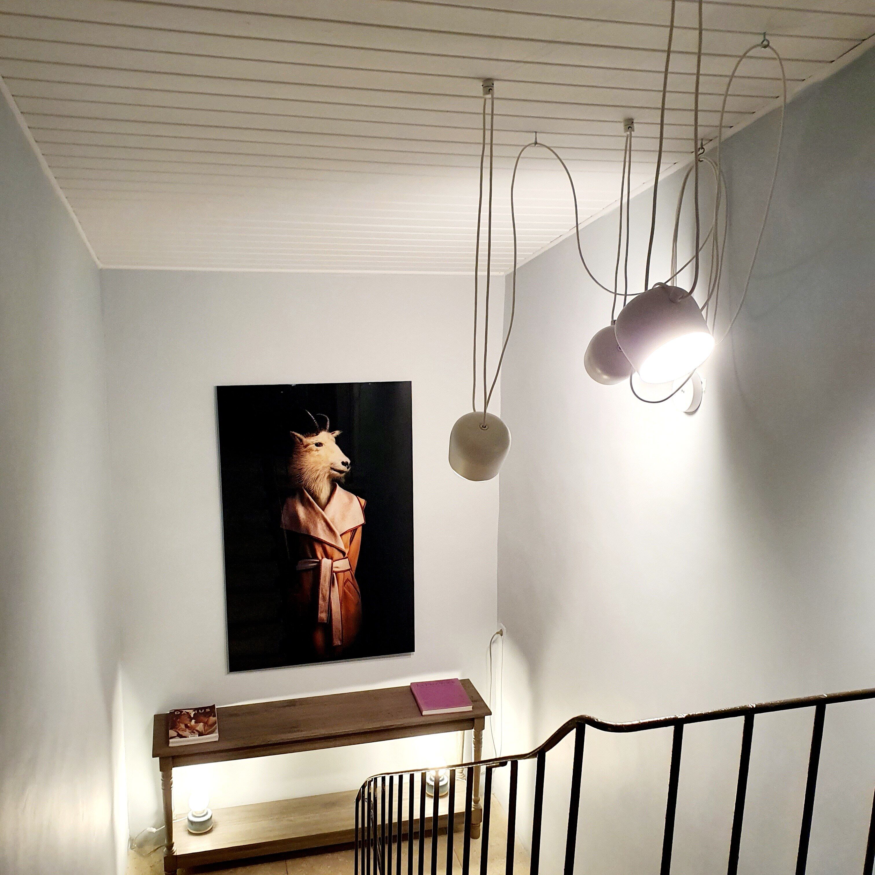 A staircase with a wooden handrail, a wall-mounted picture, and pendant lights.