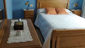 A bedroom with a wooden bed, two nightstands, a bedside table, and a wall-mounted lamp. - Piso Sencillo, Amplio y Todas las Comodidades (O Vicedo)