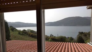 A room with large windows overlooking a lake and hills. - Piso Sencillo, Amplio y Todas las Comodidades (O Vicedo)