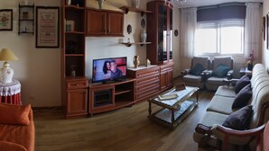 A living room with a television, wooden furniture, a red sofa, and a coffee table. - Piso Sencillo, Amplio y Todas las Comodidades (O Vicedo)