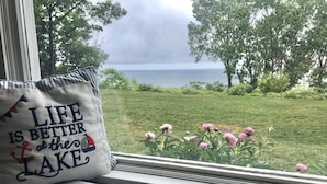 Een raamzitplaats met een kussen waarop staat: 'Het leven is beter aan het meer'.