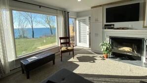 Een woonkamer met een open haard, een televisie en uitzicht op zee.