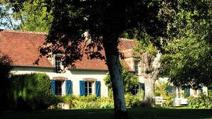 A traditional building with a red-tiled roof, a brick facade, and blue shutters. - La Ferme du Pré Martin guest room (La Genevraie)